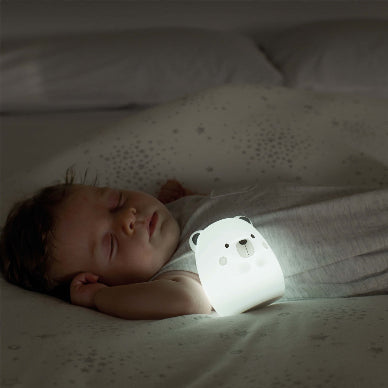 Baby lying in bed with a white bear-shaped night light.