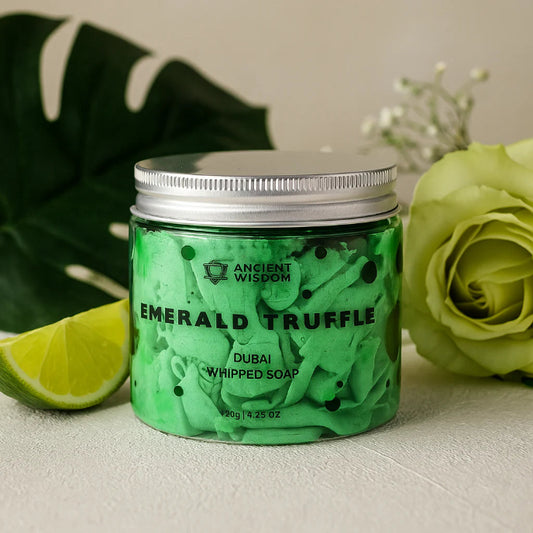 Green jar of 'Emerald Truffle' soap with a silver lid, surrounded by green leaves and a rose.