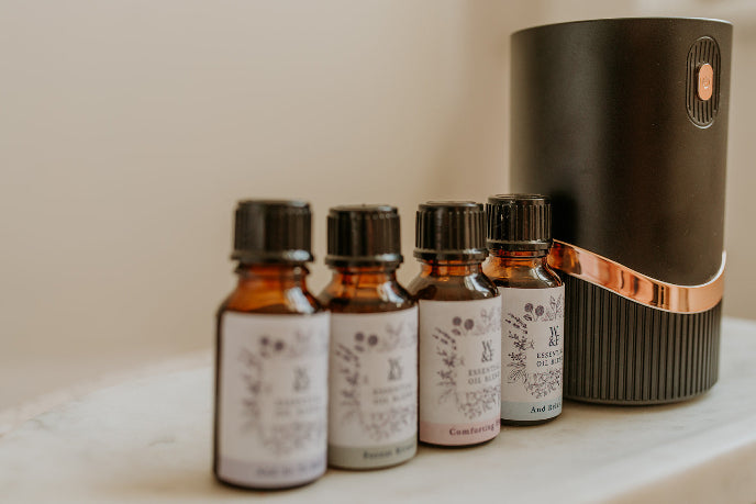 Set of small bottles with labels and a diffuser on a light surface.