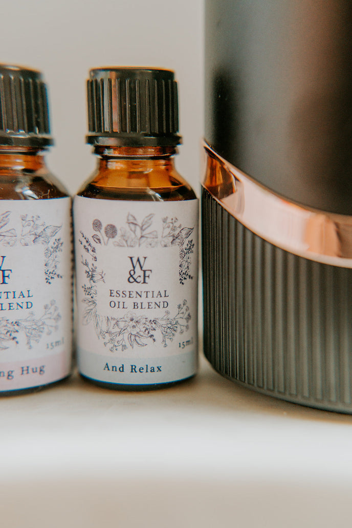 Two essential oil bottles labeled 'W & F' on a white surface with a blurred background.