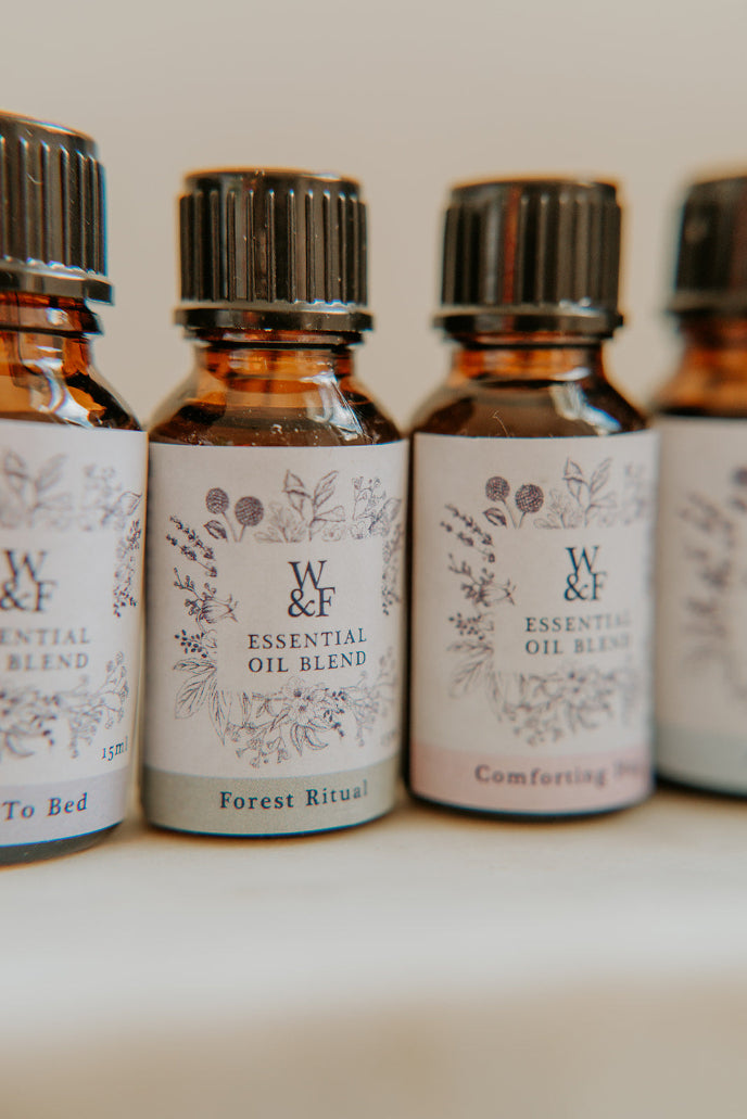 Row of essential oil bottles with decorative labels on a neutral background