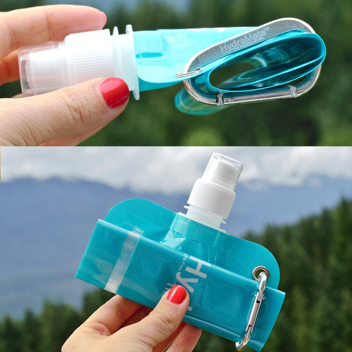 Hand holding a blue portable water bottle with a carabiner against a natural background