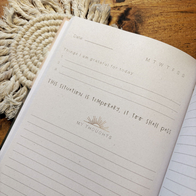 Notebook with daily journaling prompts on a wooden surface
