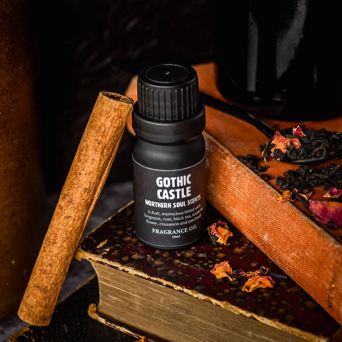 Gothic Castle fragrance oil bottle on an old book with cinnamon stick and dried flowers