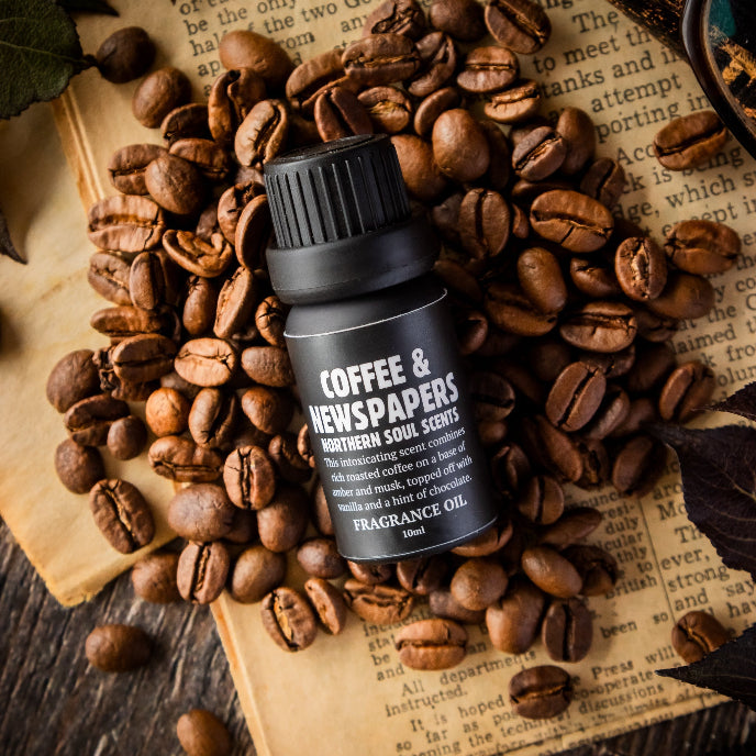 Coffee & Newspapers fragrance oil bottle surrounded by coffee beans on an old newspaper.