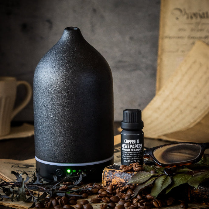 Black diffuser with a bottle labeled 'Coffee & Newspapers' on a rustic background
