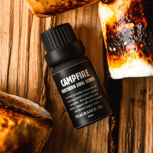 Campfire fragrance oil bottle with roasted marshmallows on a wooden surface
