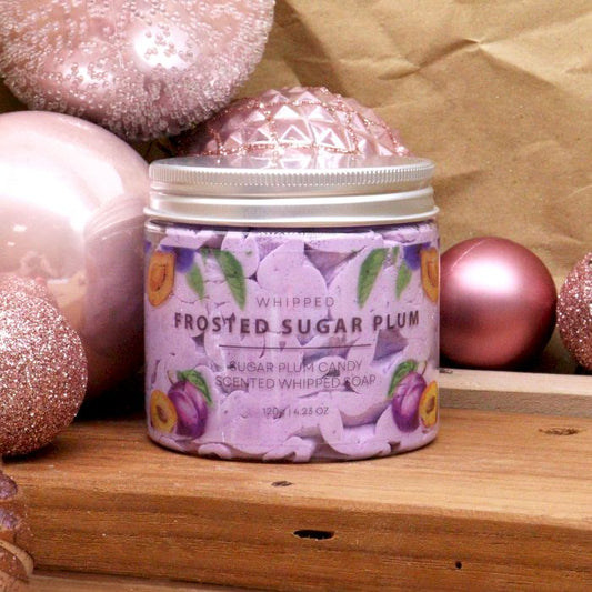 Jar of 'Frosted Sugar Plum' soap with decorative pink ornaments on a wooden surface