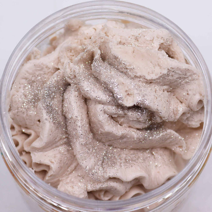 Close-up of a container filled with beige cream with glittery particles on a white background