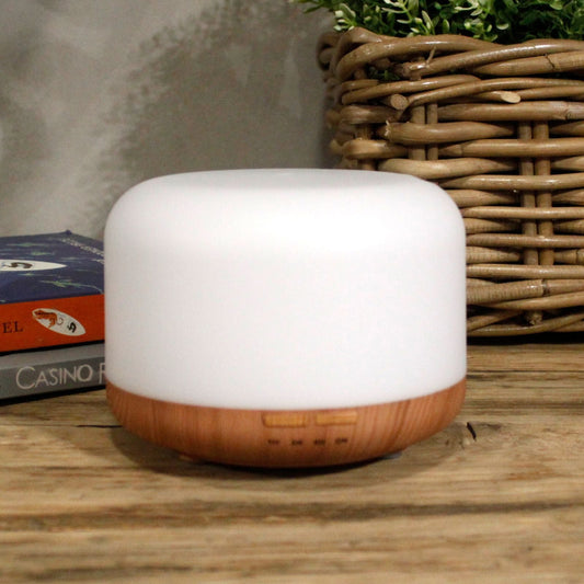 White and wooden diffuser on a wooden surface with books and a basket in the background